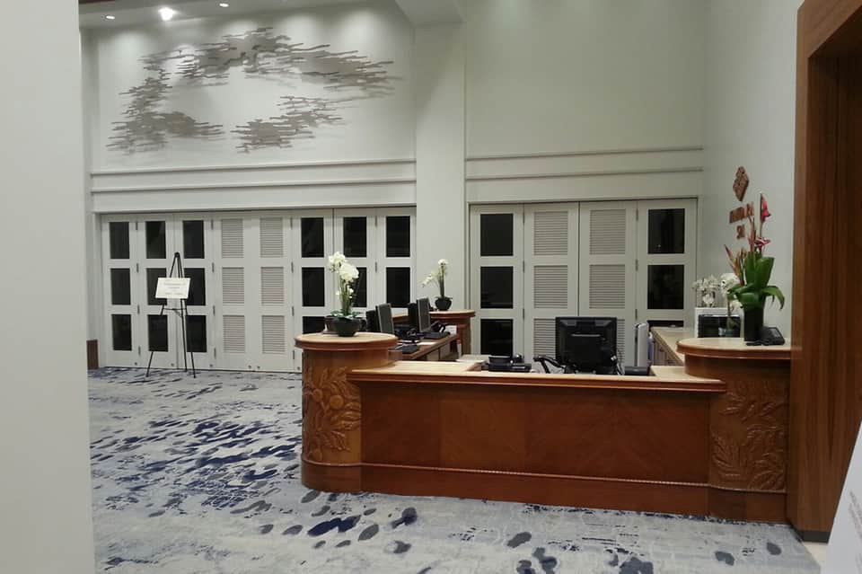 Bright lobby area with wooden reception desk, white doors, and decorative artwork