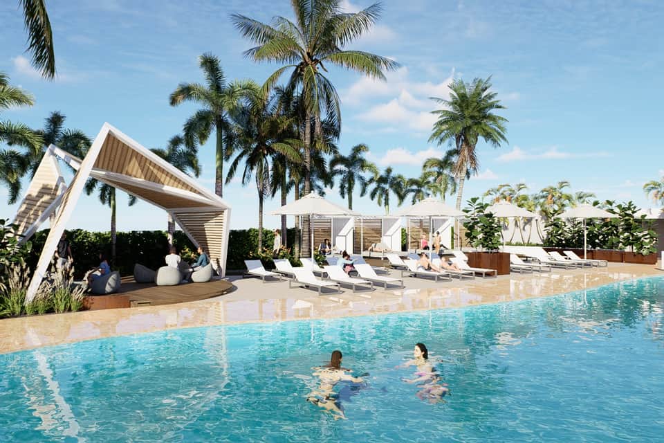 Resort pool area with modern white cabanas, lounge chairs, palm trees, and guests swimming