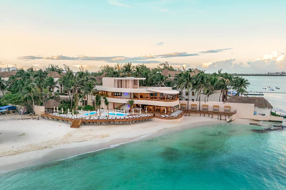 Beachfront resort with pool, lounge chairs, and modern architecture overlooking turquoise ocean