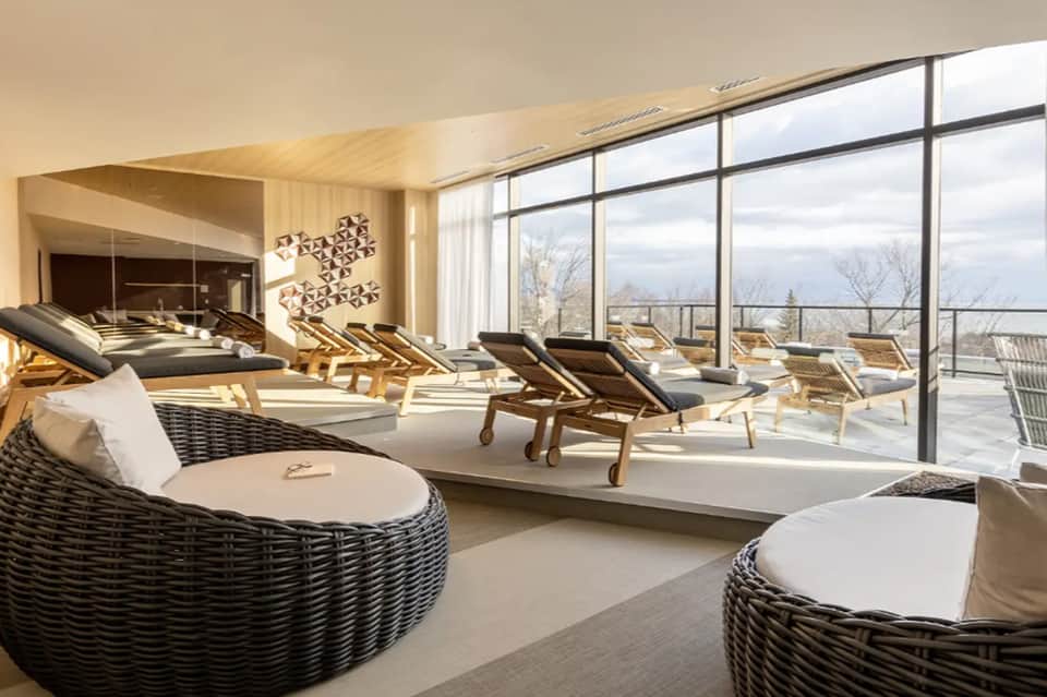 Upscale spa relaxation room with wicker seating, large windows overlooking landscape
