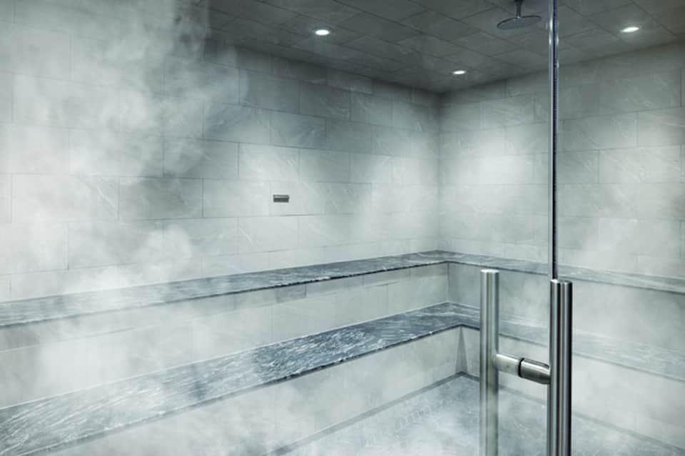Modern steam room or sauna with marble tile benches and glass enclosure