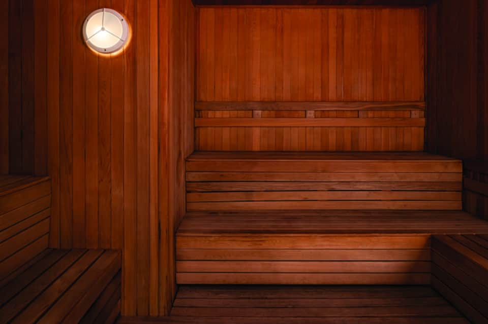 Wooden sauna interior with benches and circular porthole window