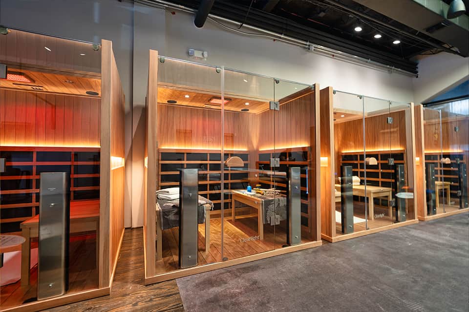 Modern spa treatment rooms with glass doors, wooden finishes, and warm ambient lighting