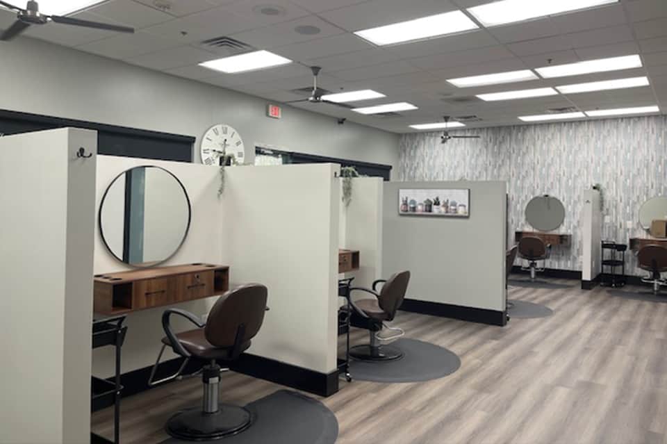Hair salon station with round mirror, wooden counter, and styled workspace with neutral walls