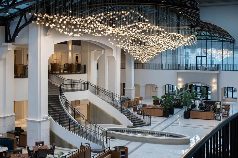 Multi-level hotel atrium with cascading pendant light installation, curved staircases, and modern architecture