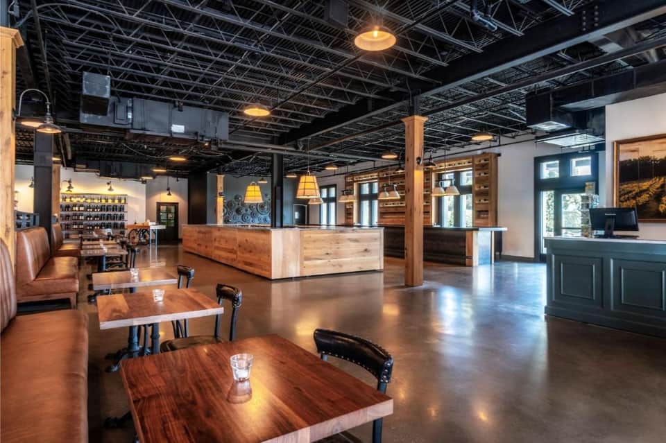 Modern bar and lounge space with exposed ceiling, wooden furnishings, and contemporary design