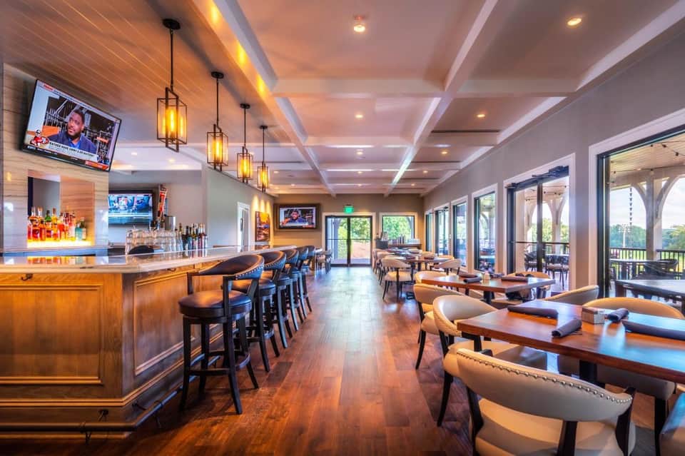 Upscale bar and lounge with wood finishes, pendant lights, and outdoor patio access