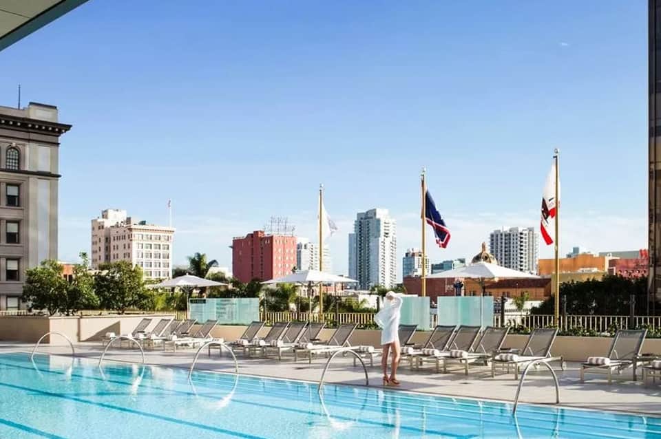 Urban rooftop pool with lounge chairs overlooking cityscape and high-rise buildings