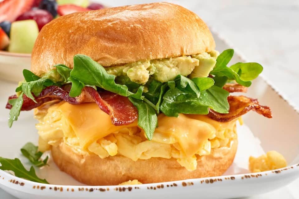 Gourmet breakfast sandwich with eggs, bacon, and avocado on brioche bun