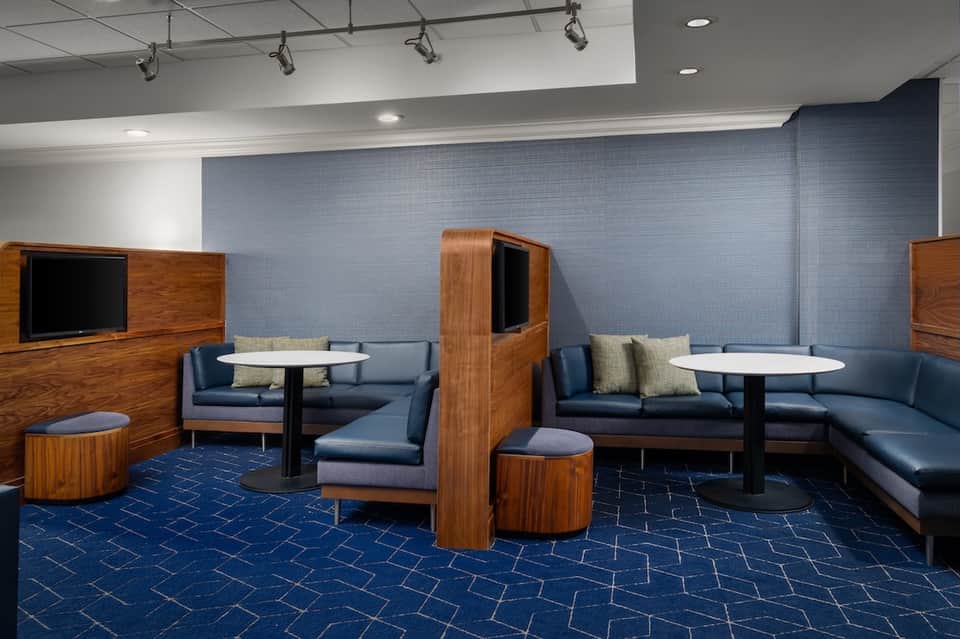 Modern lounge area with blue couches, wooden dividers, and entertainment setup