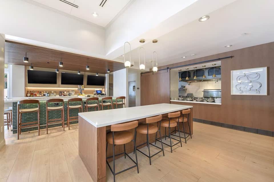 Modern kitchen and bar with wood cabinetry, green tile, and pendant lighting