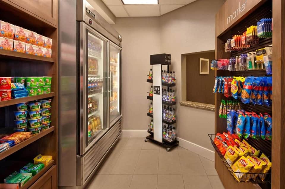 Hotel market with refrigerated beverage cases, snack shelves, and organized convenience items