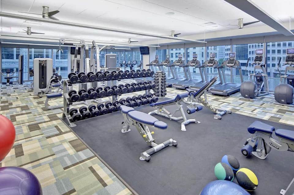 Modern fitness center with dumbbells, exercise bikes, and city skyline views