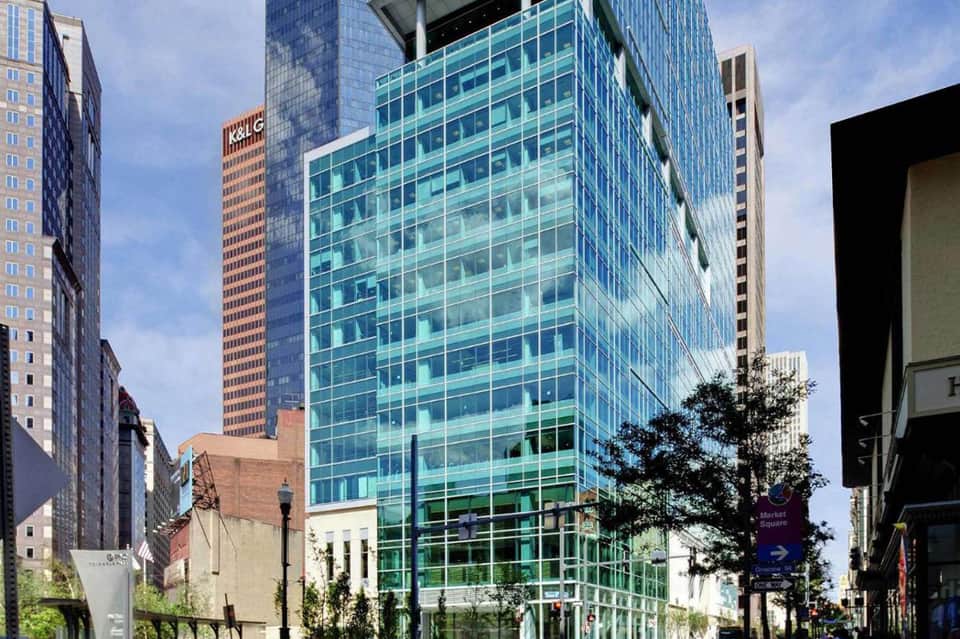 Modern glass office building exterior with green-tinted windows in urban downtown setting