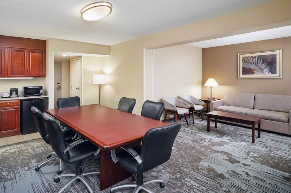 Hotel executive suite with conference table, meeting area, kitchenette, and living space