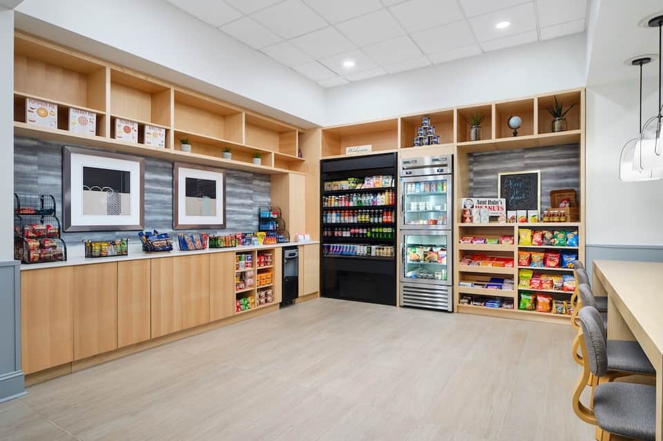 Modern hotel market shop with wooden shelving, refrigerated beverages, and snack displays