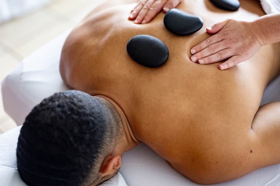 Hot stone massage treatment with therapist applying heated stones to client's back