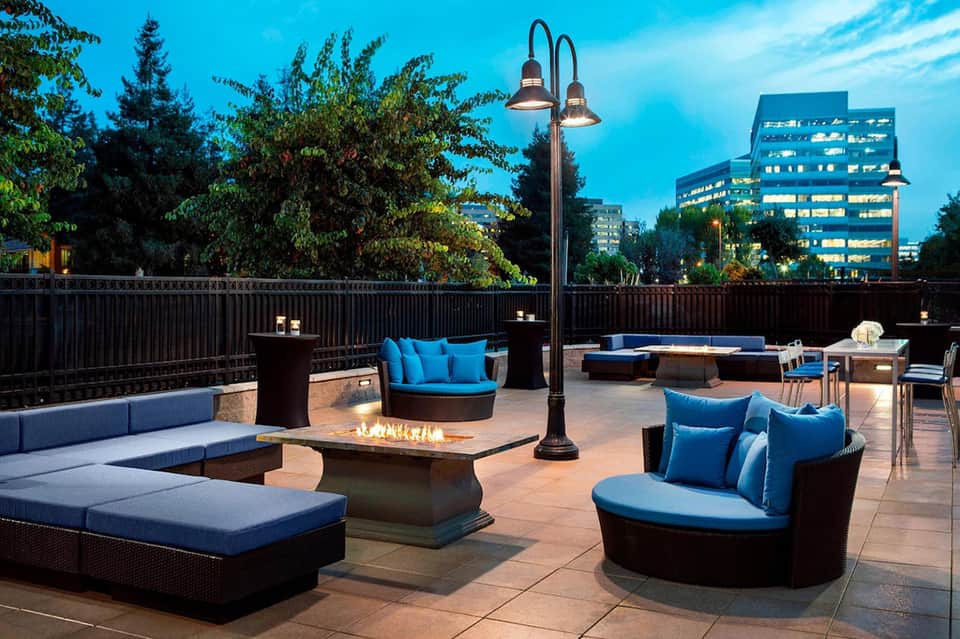 Rooftop terrace lounge with fireplace, seating, and city views at dusk
