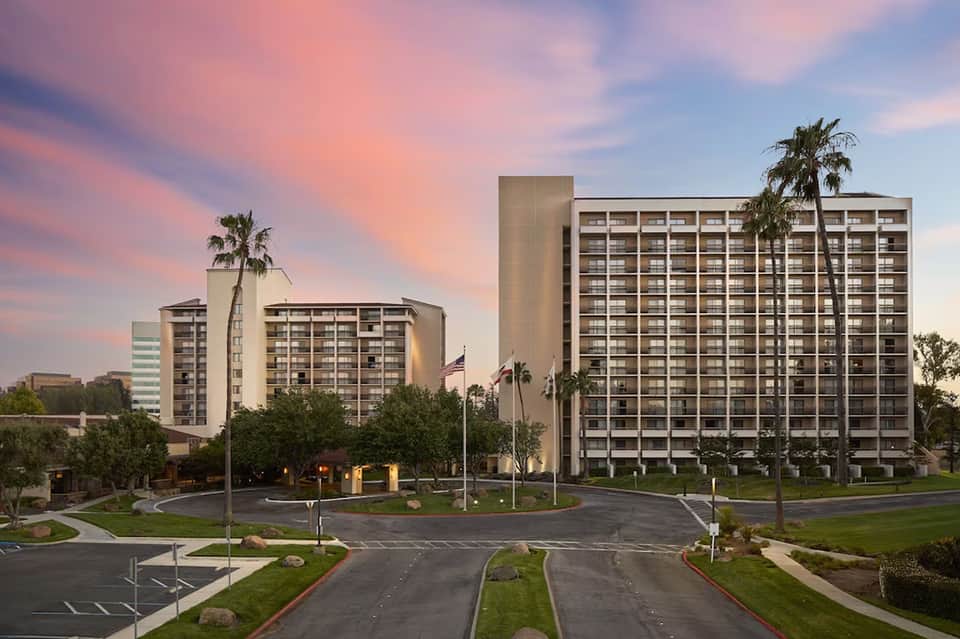 Modern hotel resort exterior at dusk with palm trees and manicured landscaping