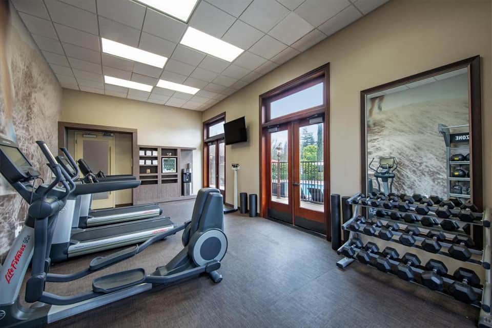Modern gym interior with treadmills, exercise equipment, windows, and mountain views