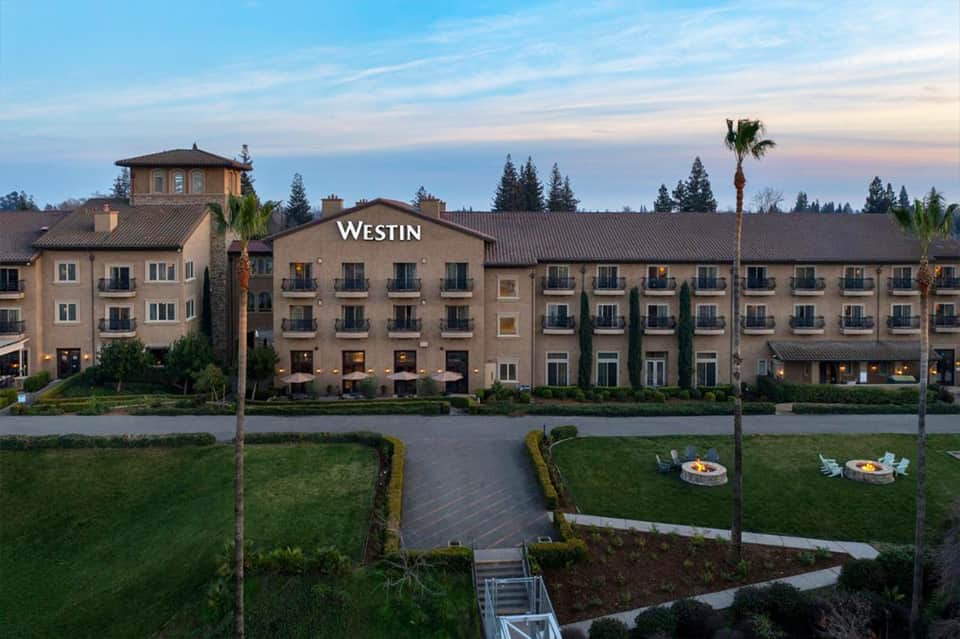 Westin hotel waterfront facade at sunset with manicured lawns and fire pit seating areas