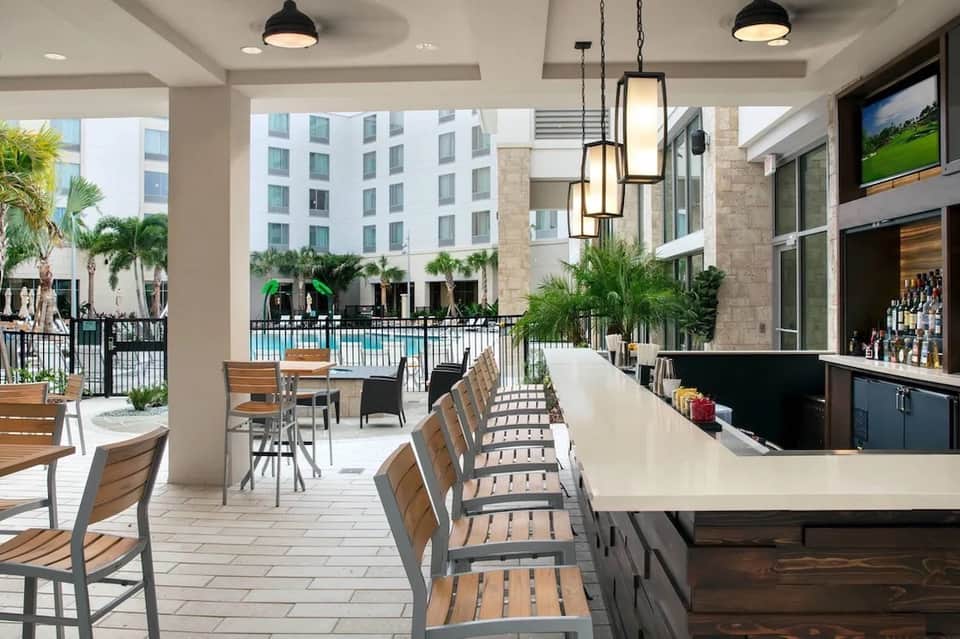 Modern pool bar with white counter, pendant lights, and resort courtyard view