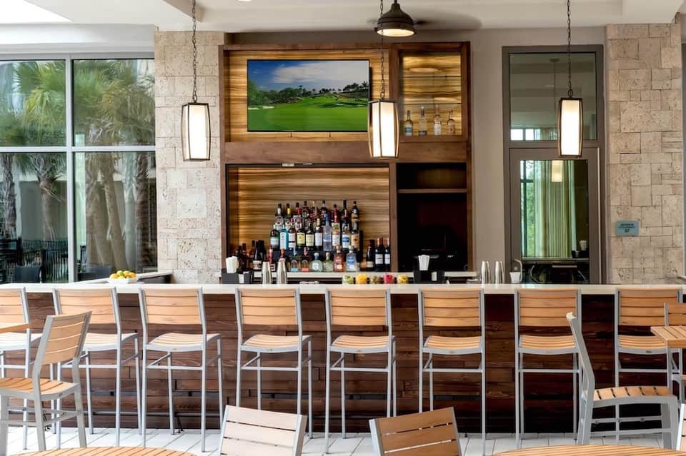 Modern resort bar with wood paneling, spirits display, and golf course view