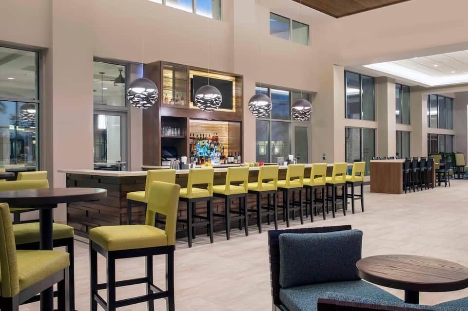 Modern hotel bar and lounge with lime green bar stools and metallic pendant lighting