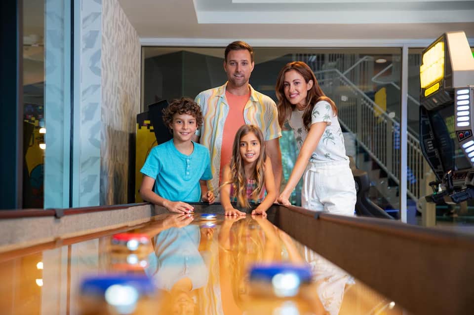 Family at hotel arcade game room with pinball machines and entertainment