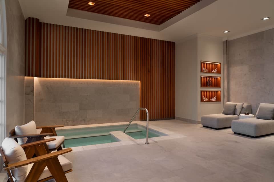 Luxurious indoor spa with soaking tub, wooden accents, ambient lighting, and lounge seating