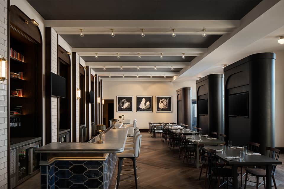 Elegant private dining room with long table, black accent walls, artwork, modern lighting, floor-to-ceiling windows