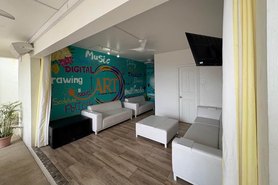 Modern lounge space with colorful art wall, white furniture, wooden flooring, and flat-screen TV