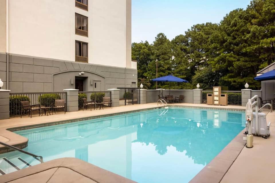 Indoor rectangular pool with blue water, lounge chairs, and hotel building exterior