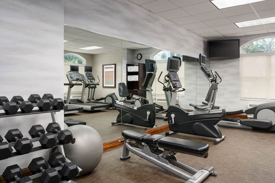 Fitness center with cardio equipment, dumbbells and mirrored walls