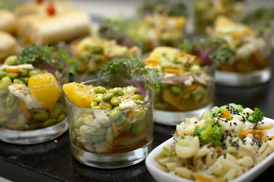 Gourmet appetizers including asparagus salad in glasses and pasta dishes with microgreens