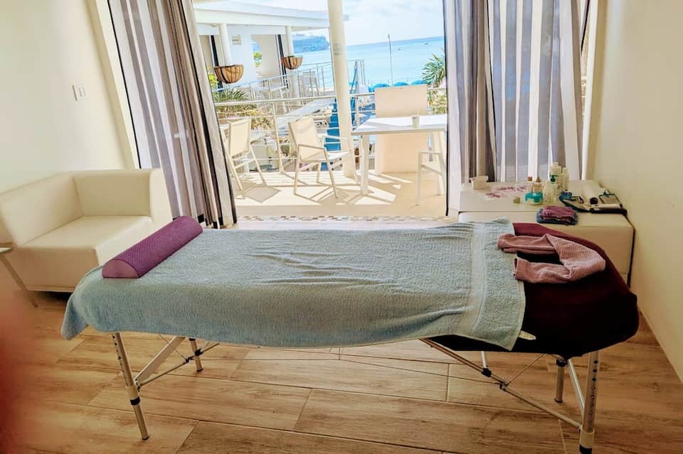 Beachfront hotel room with ocean views from balcony, bed with colorful pillows, and seating area
