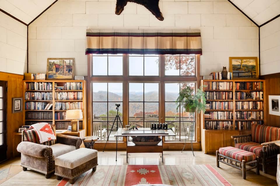Elegant library room with floor-to-ceiling bookshelves, mountain view windows, and upholstered seating