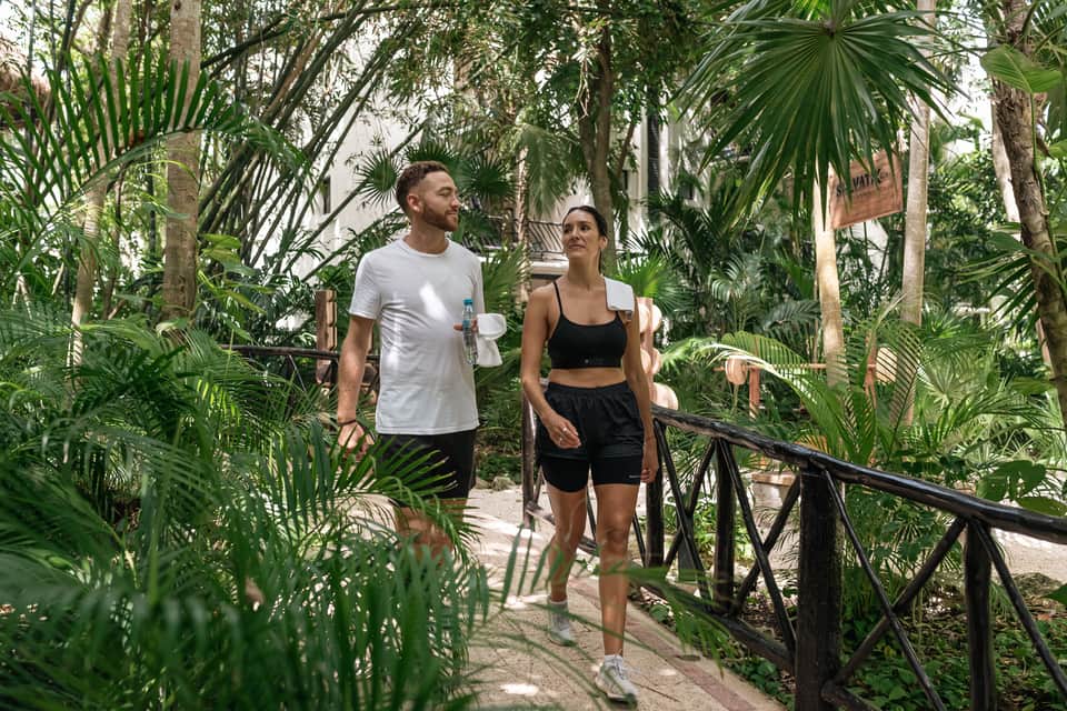 Couple jogging on palm tree-lined path through tropical resort grounds