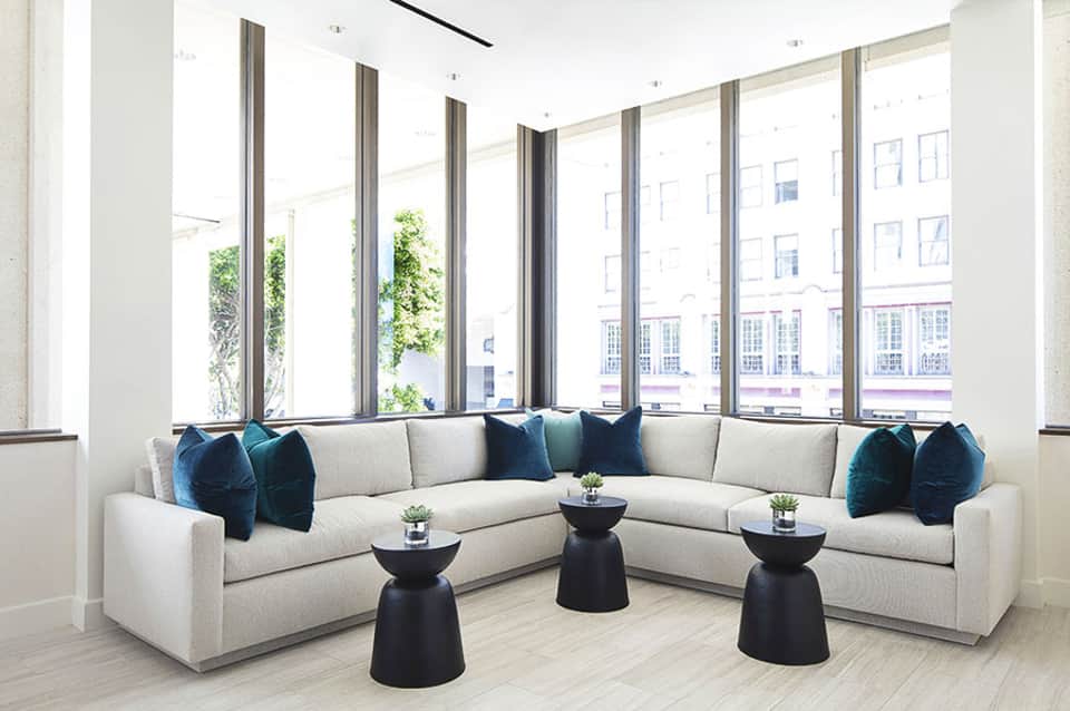 Modern living room with curved cream sectional sofa, navy pillows, and floor-to-ceiling windows