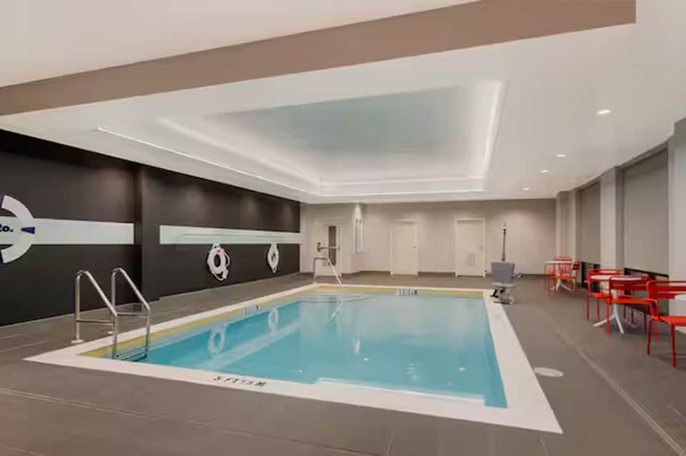 Indoor lap pool with modern minimalist design, white ceiling, and safety railings