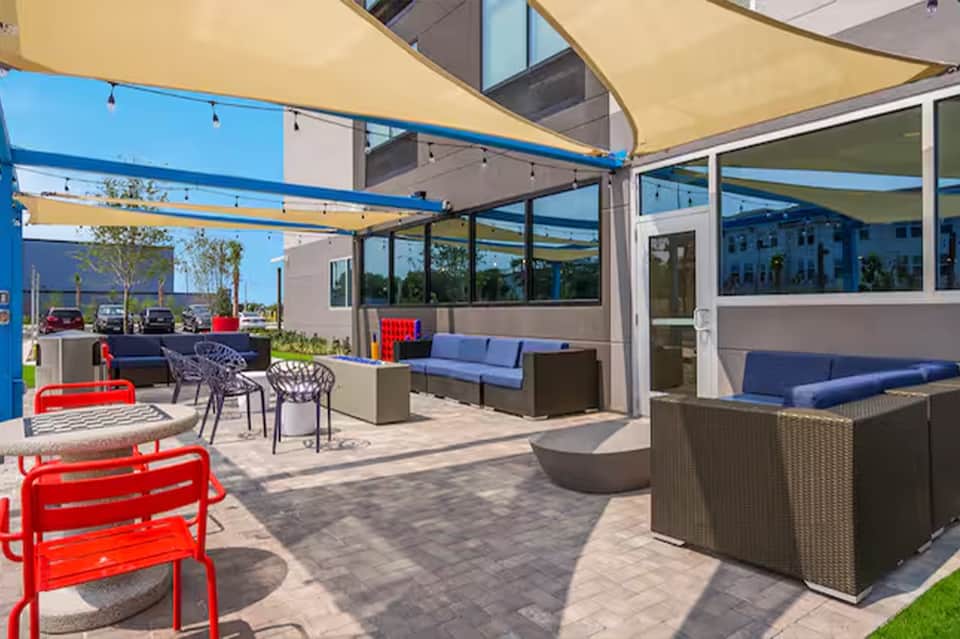 Outdoor terrace with colorful seating, sail shade structures, and modern resort architecture