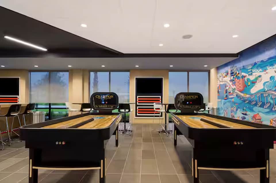 Game room with two pool tables, arcade games, and large windows with scenic views