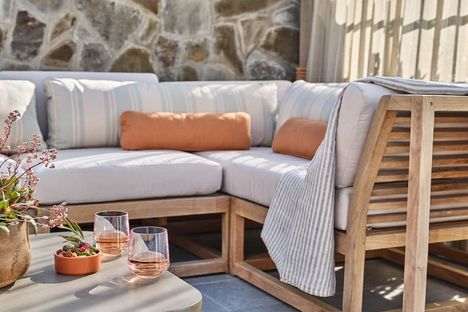 Outdoor sectional sofa with striped cushions and stone accent wall overlooking water