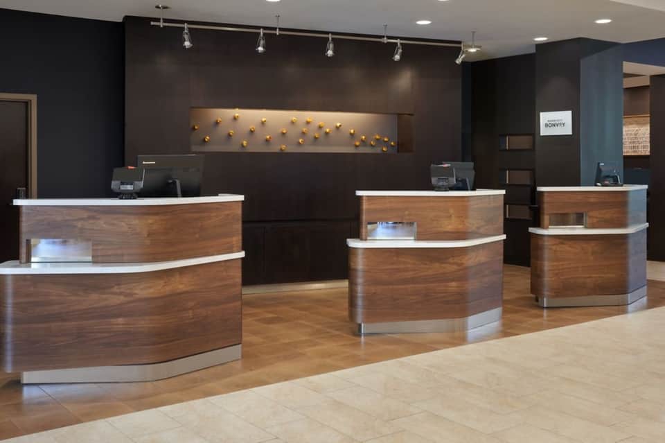 Hotel reception area with three curved wooden desks and modern lighting fixtures