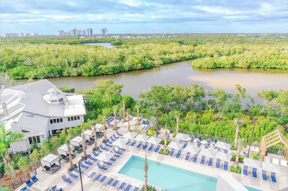 Aerial view of resort pool and deck overlooking mangrove wetlands and distant city skyline