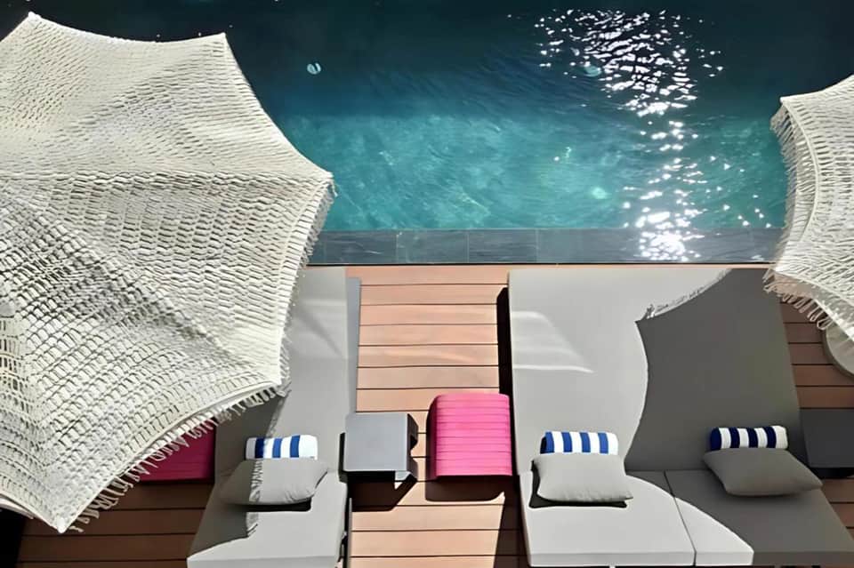 Overhead view of spa relaxation area with white textured lounge chairs, striped cushions, and turquoise water