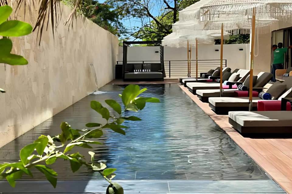 Narrow residential pool surrounded by loungers and modern white buildings