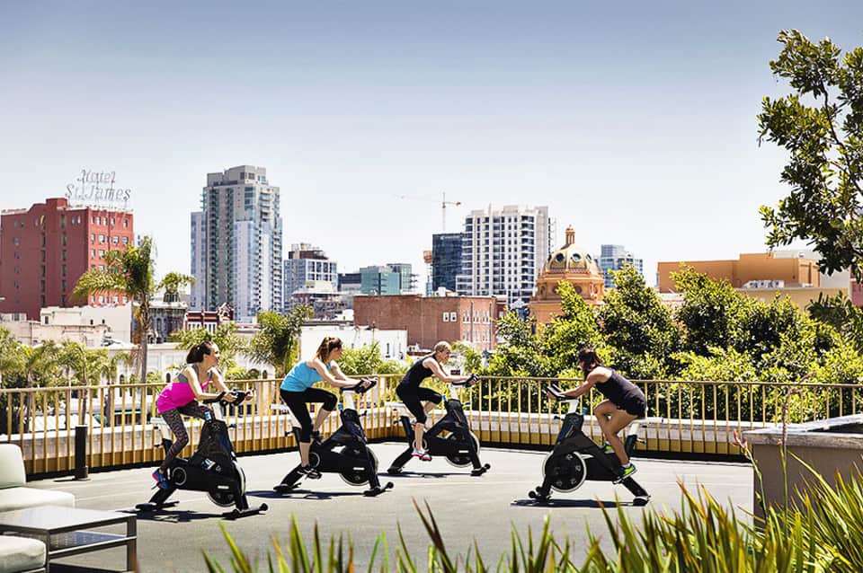 Group fitness class on stationary bikes with urban skyline view
