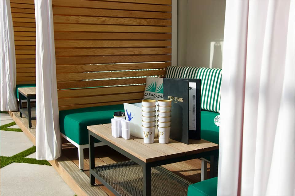 Modern outdoor lounge area with green seating, wood privacy screen, and striped cushions