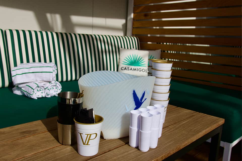 Resort cabana interior with green striped bedding, branded pillows, amenities, and wooden slat ceiling details